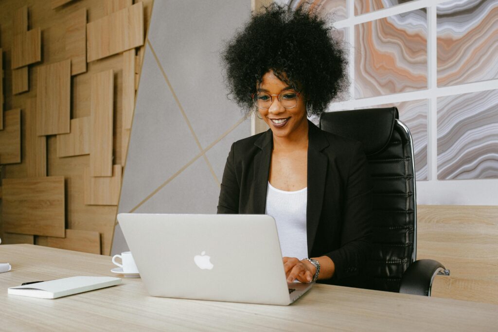 Smiling woman working remotely on a laptop in a stylish office setting.